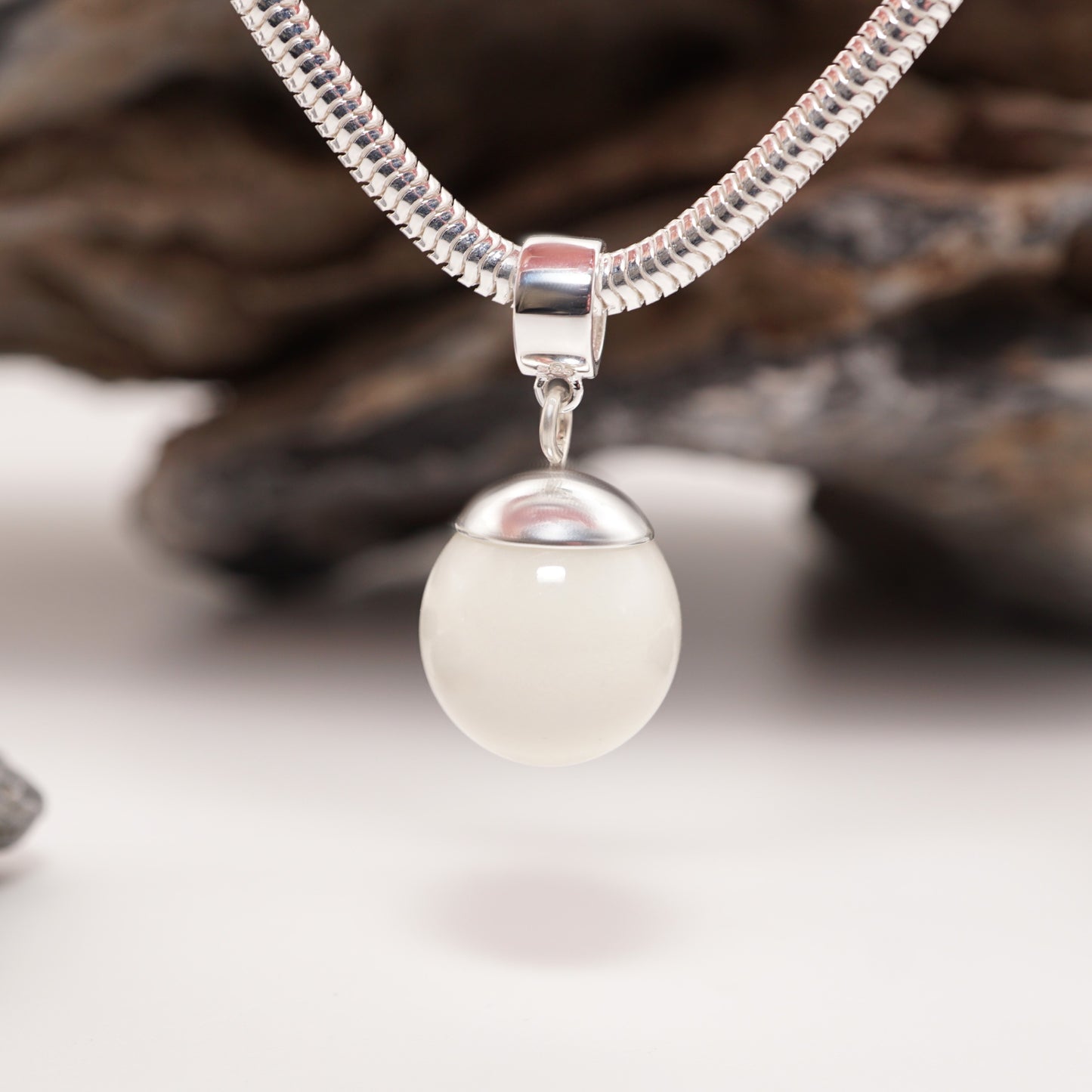 Elegant Orb Keepsake Pendant with a 13mm semen-infused resin sphere, suspended on a sterling silver snake bracelet.