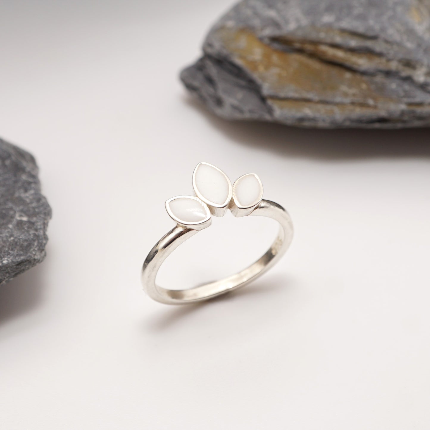 Sterling silver Petal Keepsake Ring with semen inlays, displayed against a natural stone backdrop for a timeless and bold jewellery aesthetic.