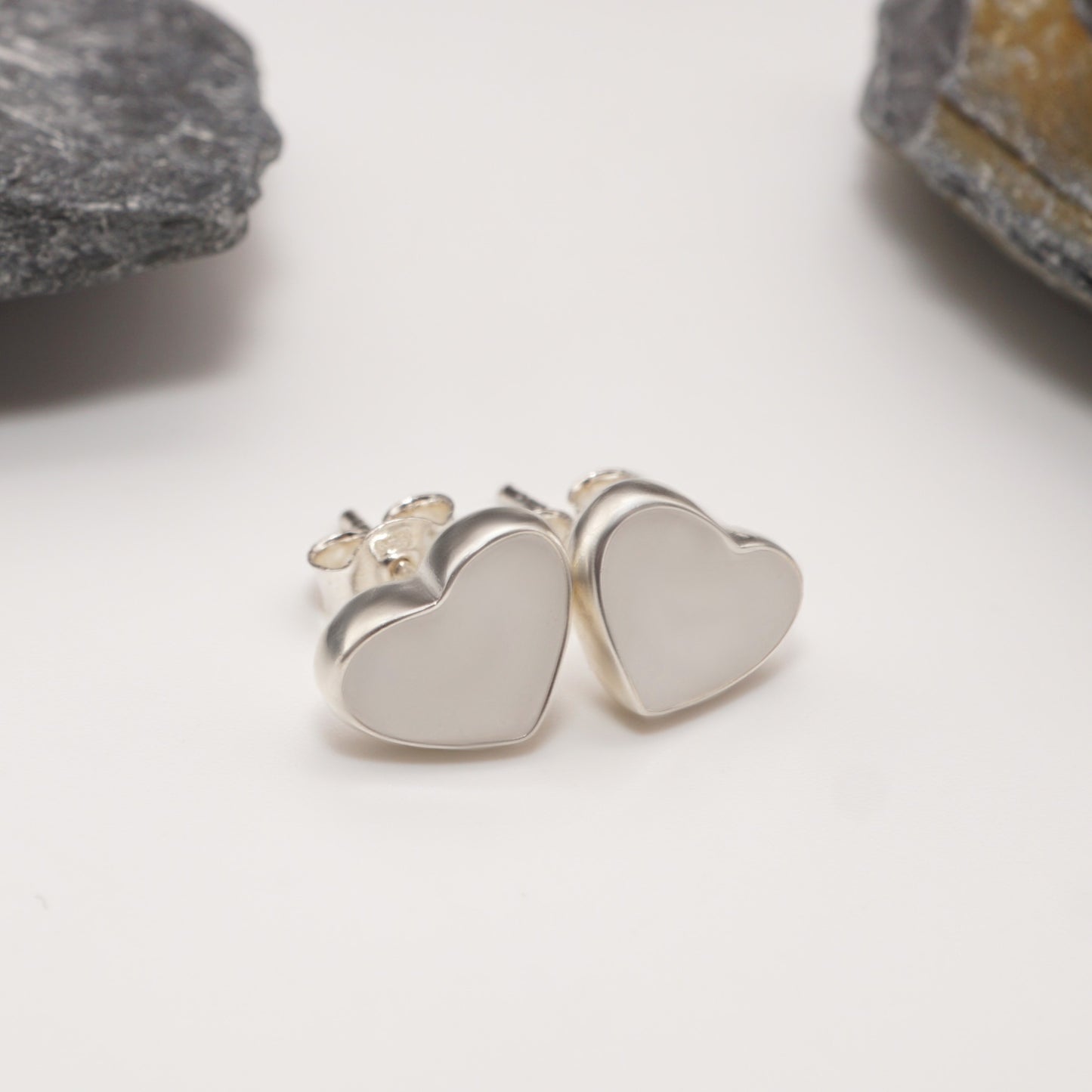 Close-up of heart keepsake earrings in polished sterling silver, featuring sleek design and custom sperm inlays for spicy jewellery lovers.