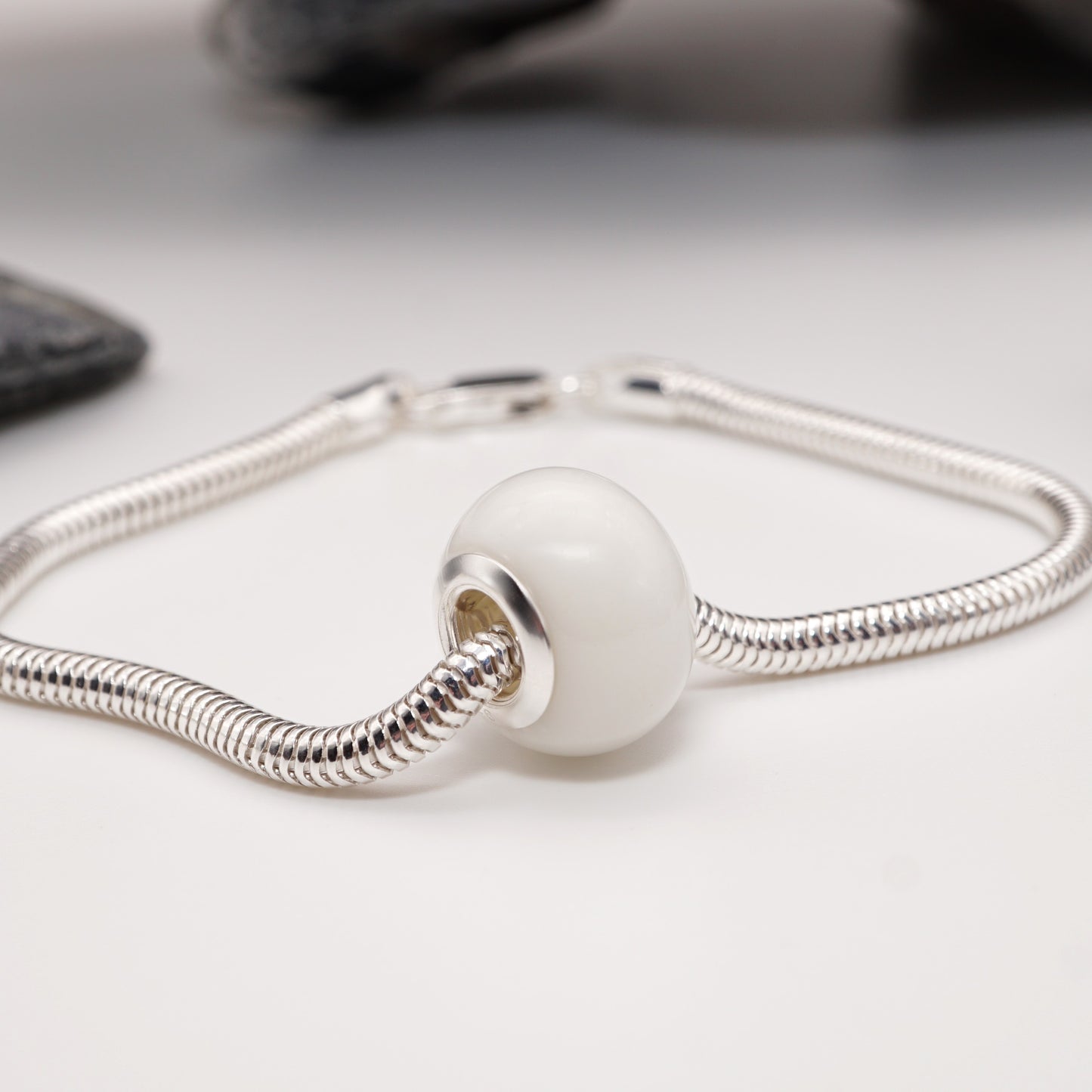 Lust Bead featuring a smooth semen-infused resin core, finished with sterling silver or gold-plated grommets