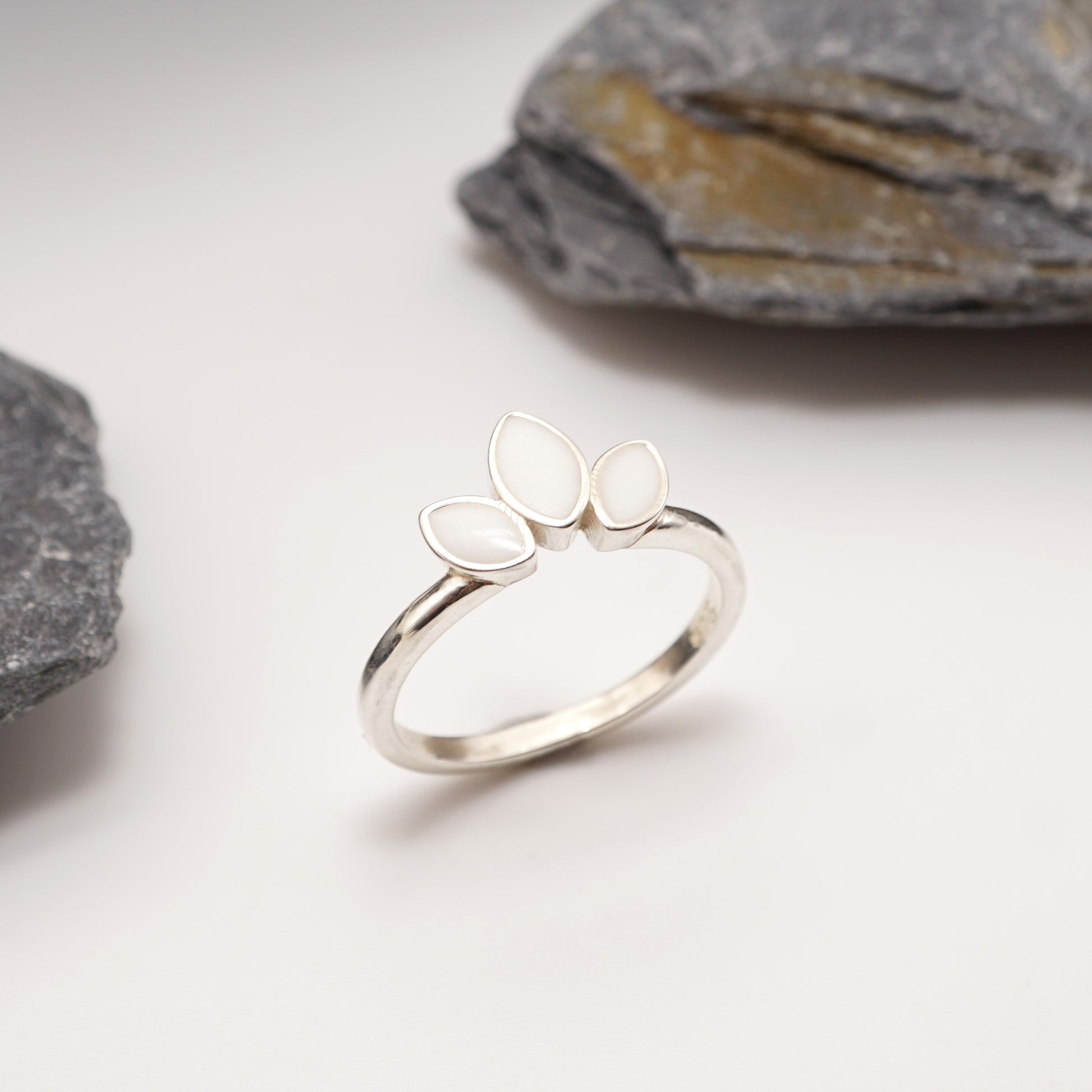 Sterling silver Petal Keepsake Ring with semen inlays, displayed against a natural stone backdrop for a timeless and bold jewellery aesthetic.