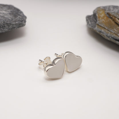 Zoomed-in shot of sterling silver heart earrings showcasing their polished finish and daring custom semen inlays.