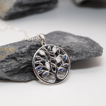 Tree of Life pendant in sterling silver featuring customisable semen inlays and CZ stones, displayed against a natural stone backdrop.